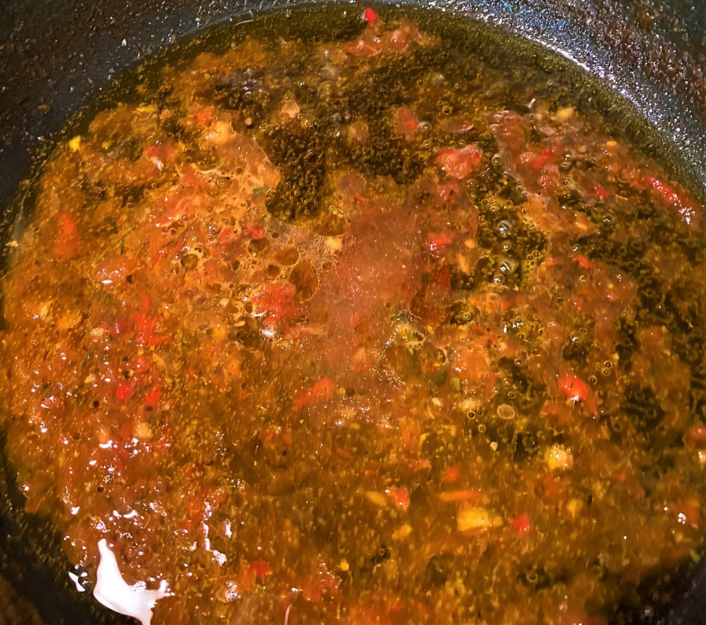 liquid from raw adjika with olive oil and sugar in a frying pan