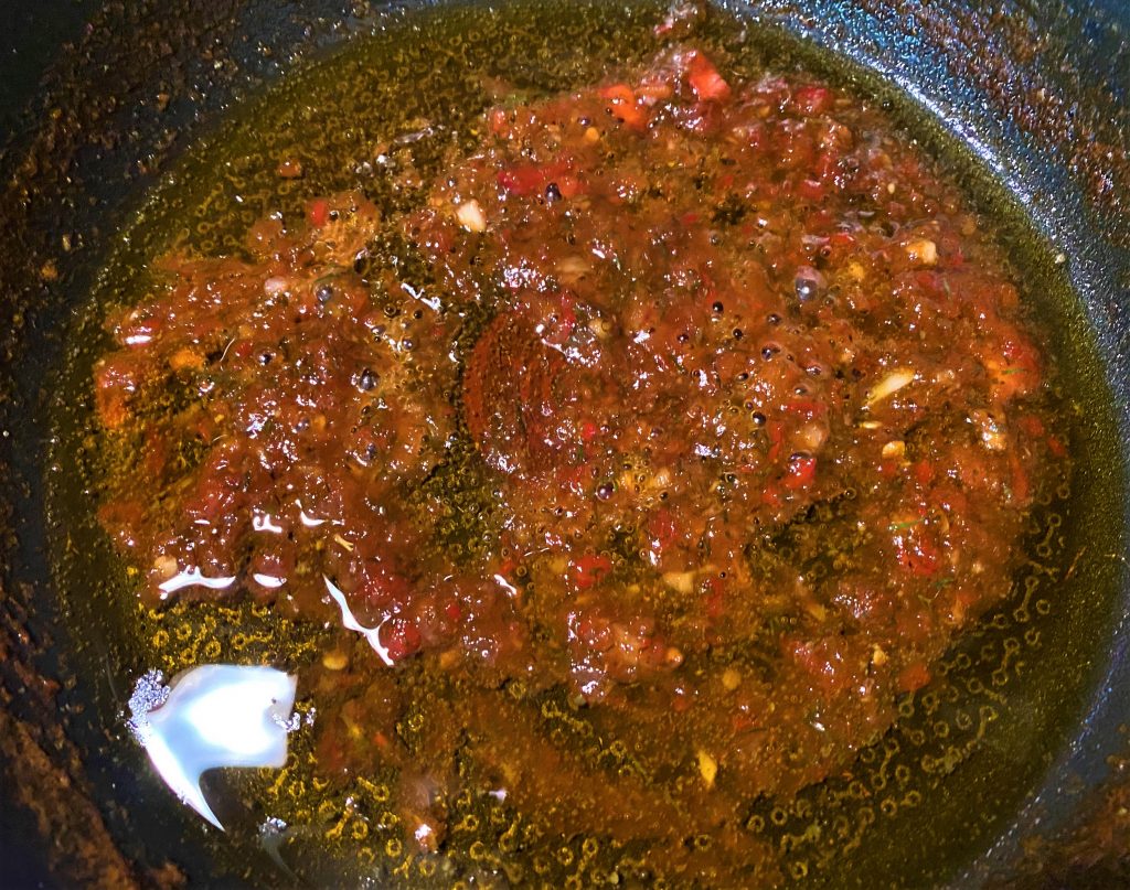 liquid from raw adjika with olive oil and sugar in a frying pan